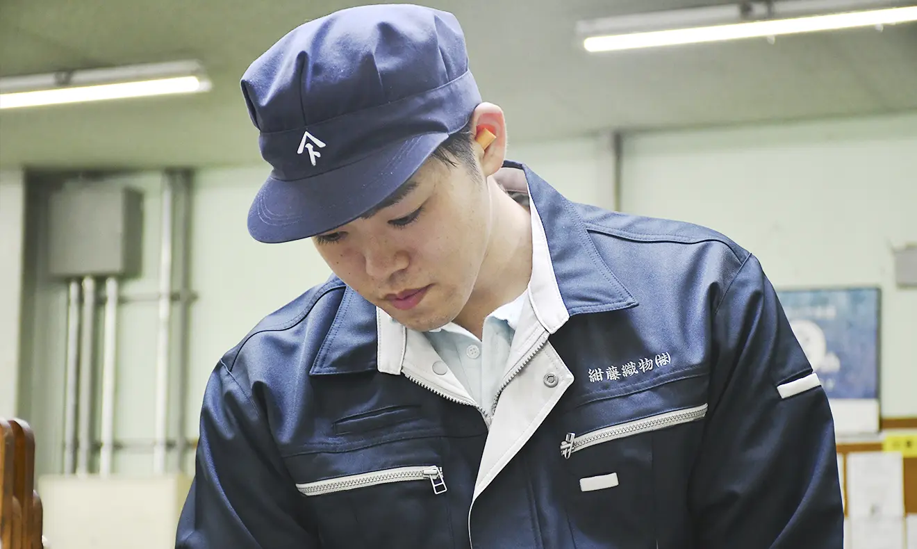 作業服と帽子を着用した男性社員が、真剣な表情で作業に取り組んでいる。