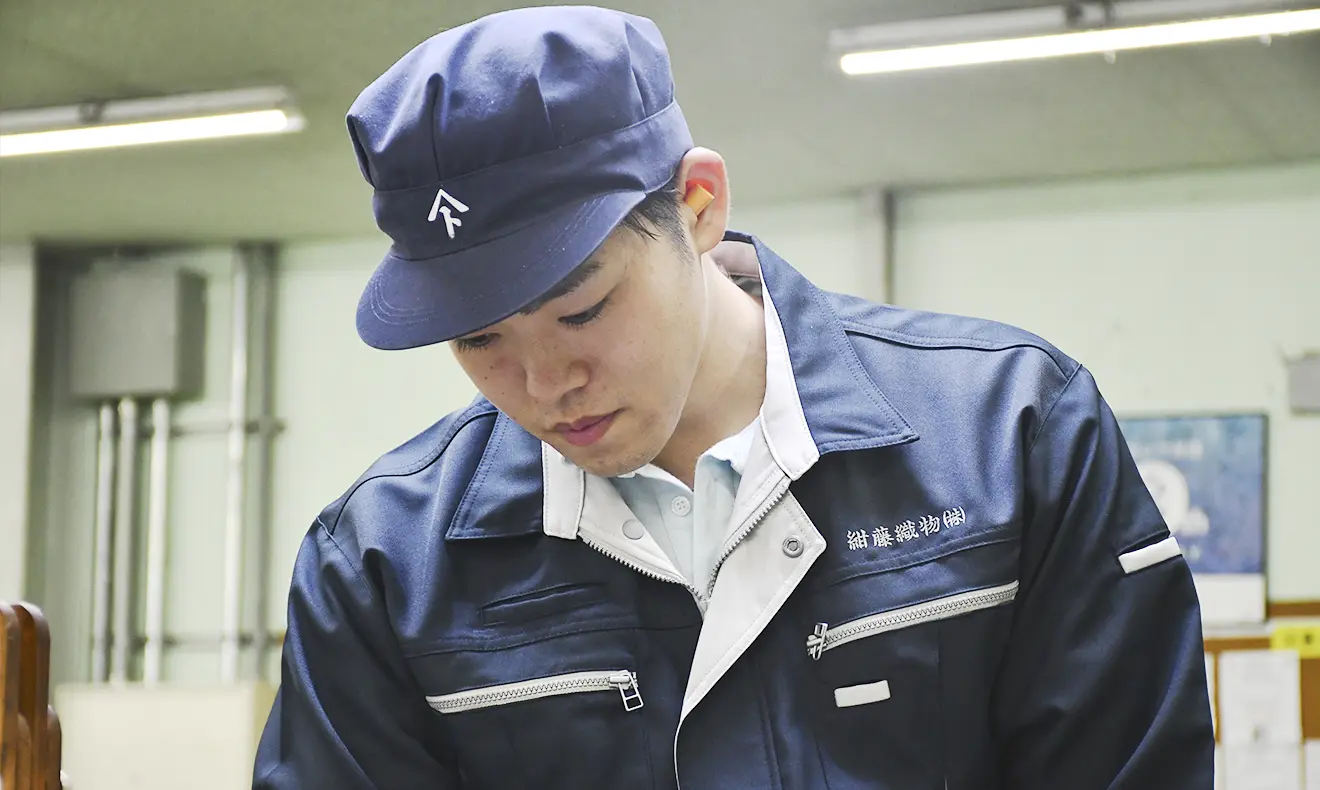 作業服と帽子を着用した男性社員が、真剣な表情で作業に取り組んでいる。